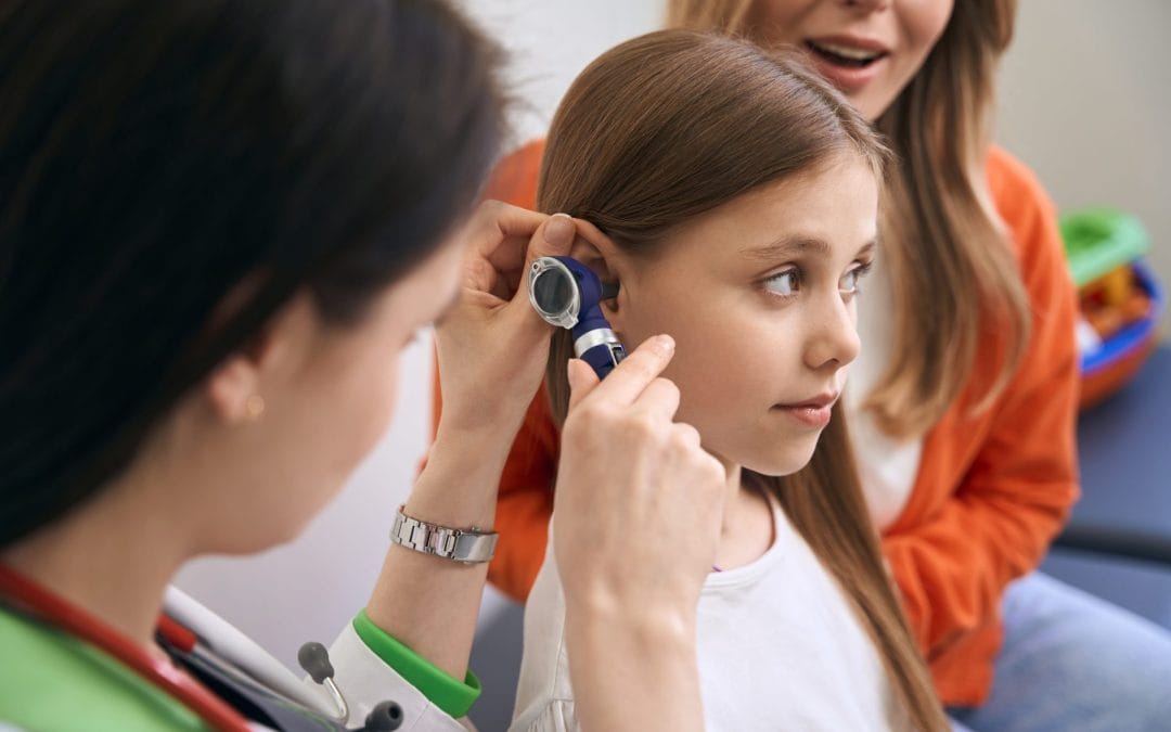 A young girl having her ear examined by a healthcare professional.